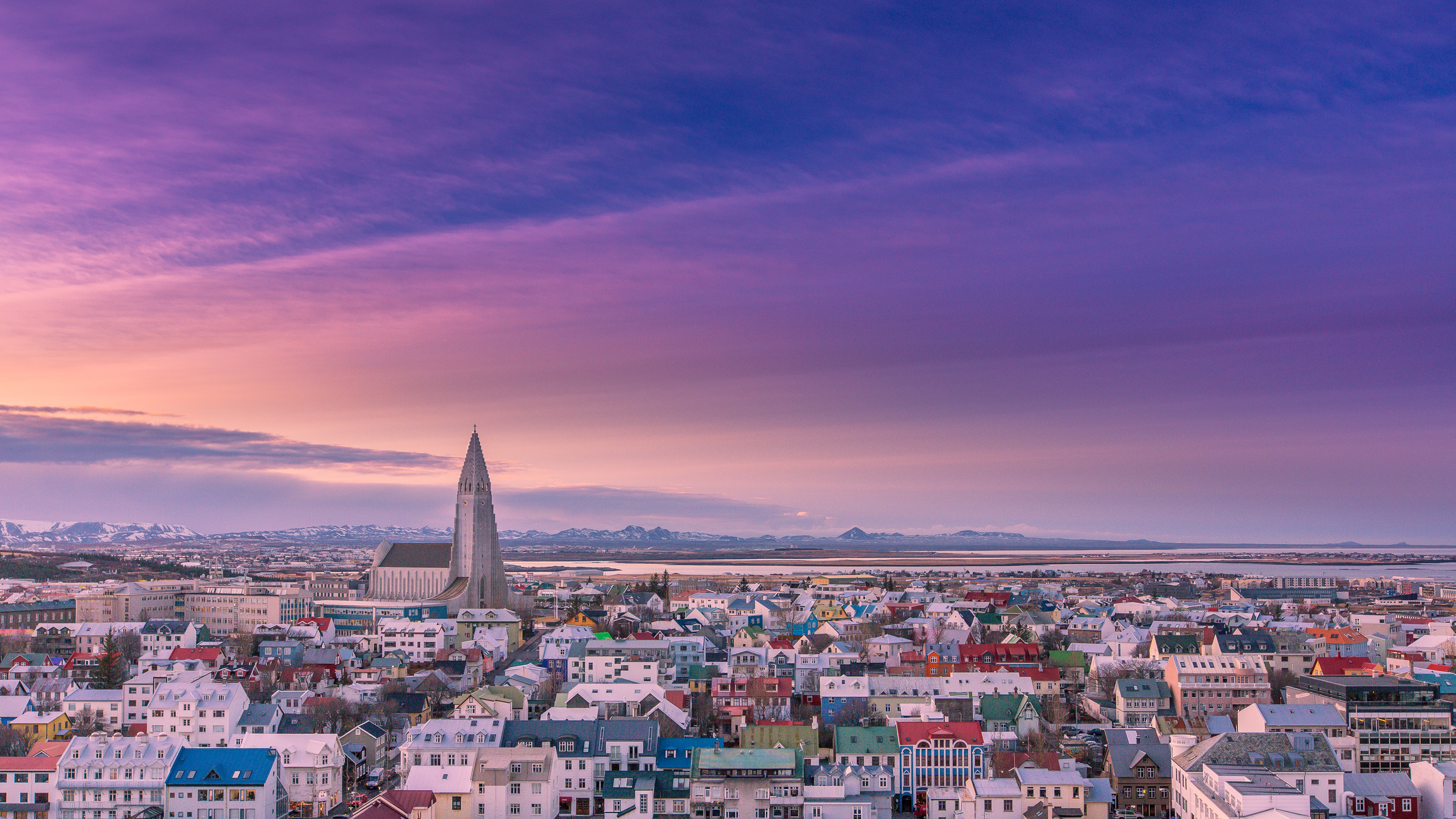 Vue aérienne de Reykjavík au lever du soleil, entre mer et montagnes.